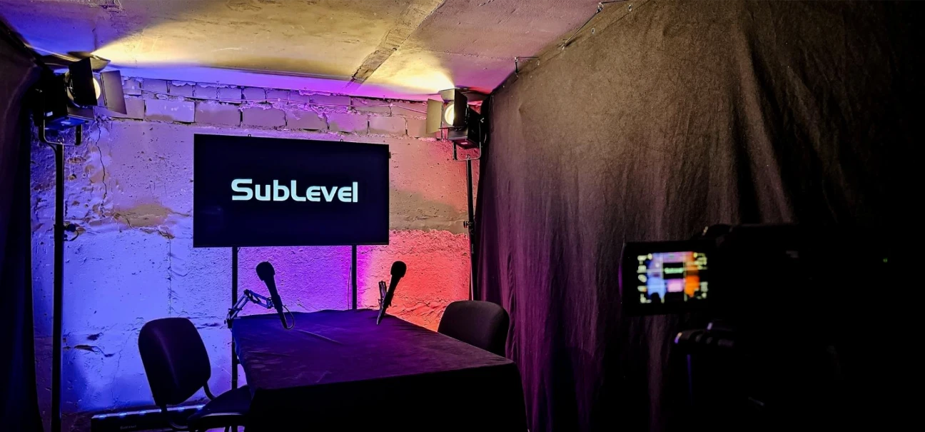 Divu personu PRO podkāsta studijas uzstādījums ar industriālu fonu, LED stieņiem, prožektoru un 48 collu LCD ekrānu Rīgā